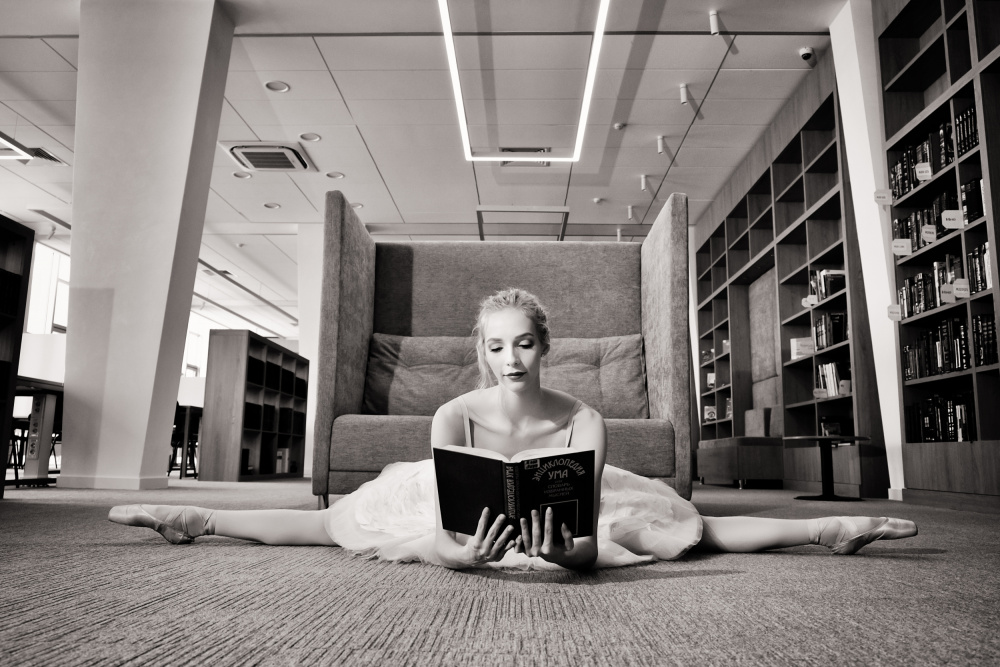 the Dreamer. ballerina on pointe shoes in the library reads a book holding it up von Alexandr