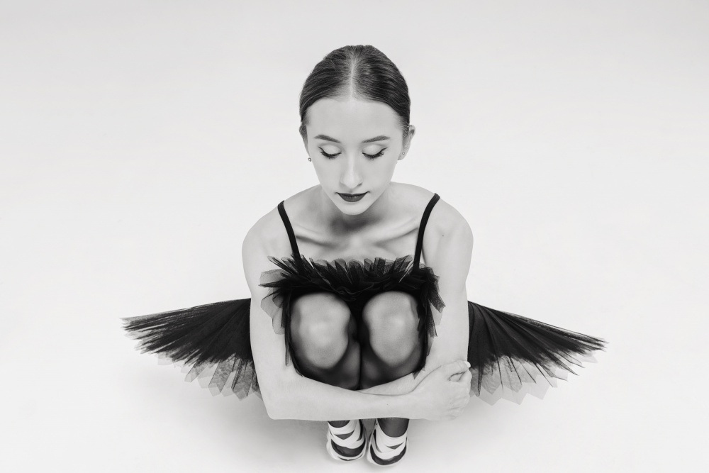 a portrait of a ballerina in a black tutu squatting hugging her knees von Alexandr