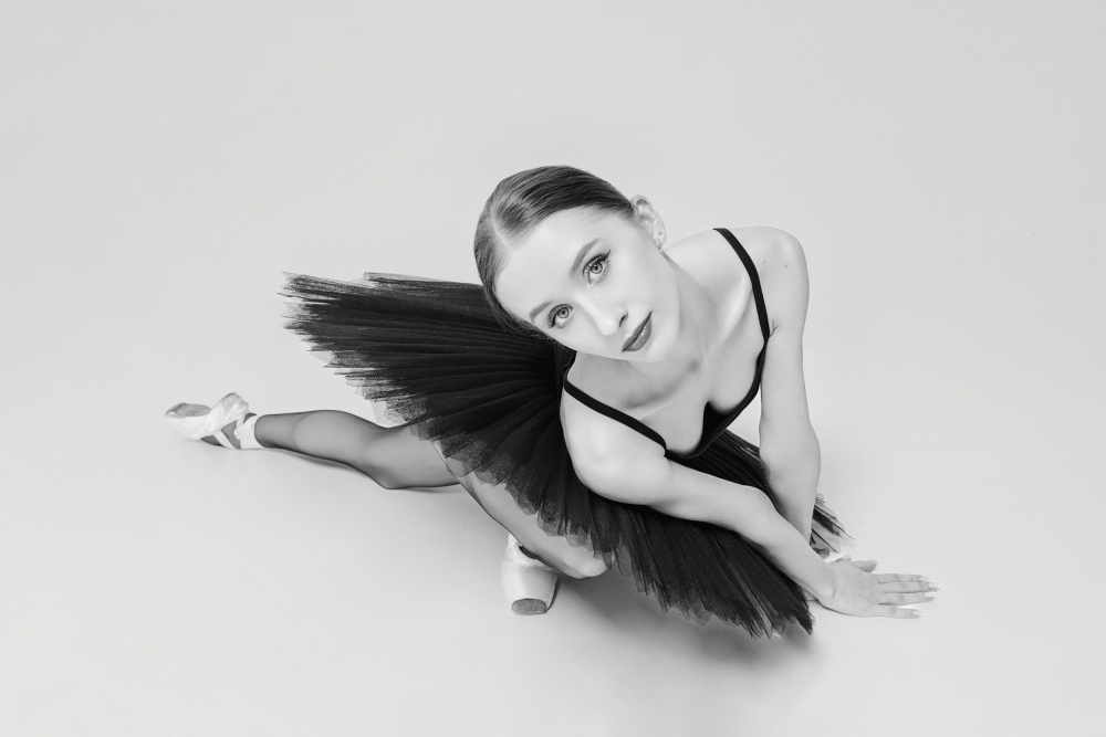 portrait of a ballerina in a black tutu lying on the floor leaning on her hands top view von Alexandr