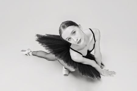 portrait of a ballerina in a black tutu lying on the floor leaning on her hands top view