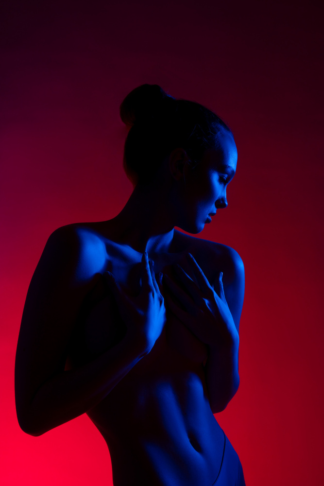 Young woman in casual clothes standing under neon light von Andrey Guryanov