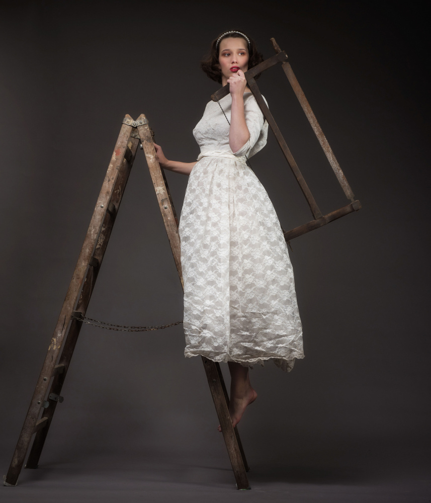 Rosa in weddingdress with saw on ladder von Axel K. Schoeps