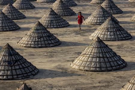 Children run amongst hundreds of traditional rice mills made from bamboo