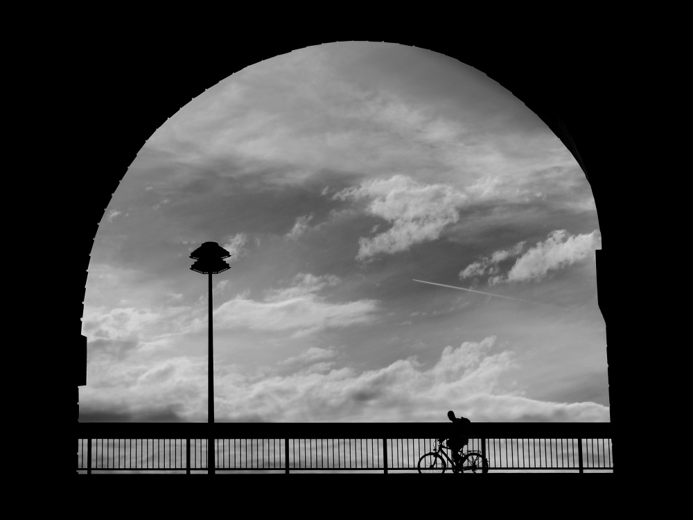 Cyclist, clouds and street lamp in the arch von Eiji Yamamoto