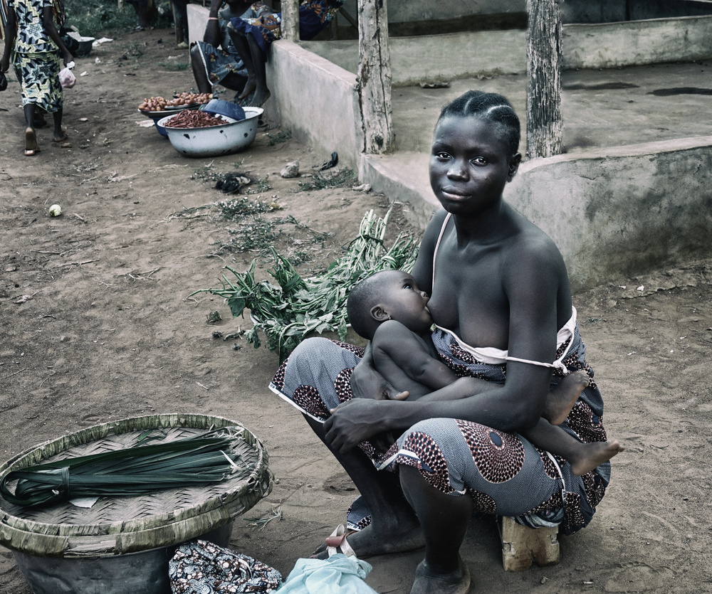 Breastfeeding her child in the market (Benin) von Elena Molina