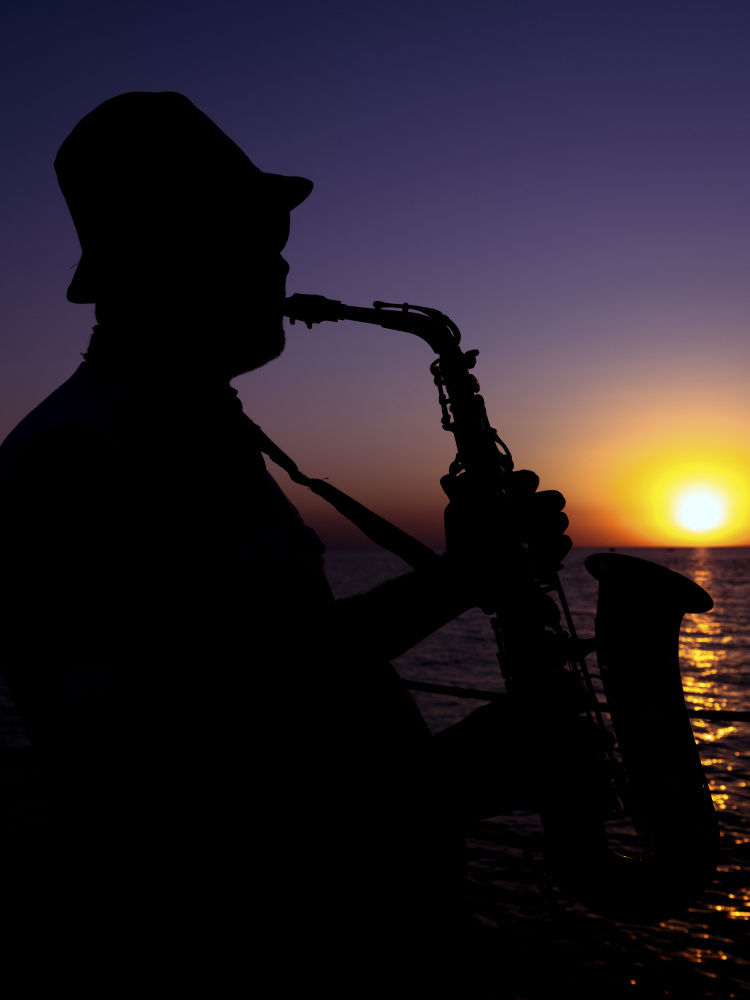 a musician playing the saxophone at sunset von engin akyurt