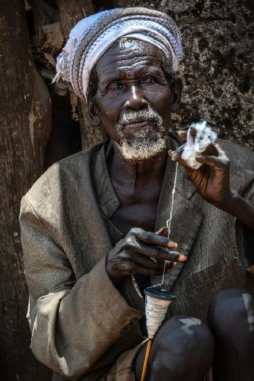 Old man spinning wool