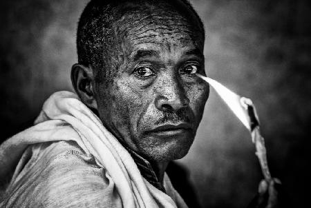 Ethiopian man holding a lit candle in a religious ceremony.