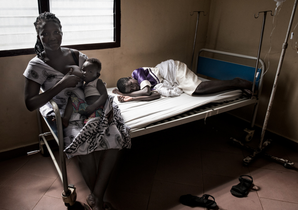 A grandmother breastfeeds her grandson while visiting her sick daughter - Ghana von Joxe Inazio Kuesta Garmendia