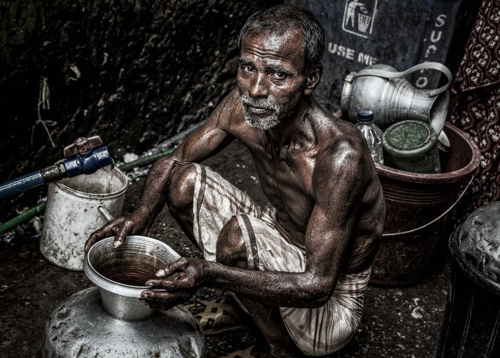 Man filling a pitcher with water in the streets of Bangladesh. von Joxe Inazio Kuesta Garmendia