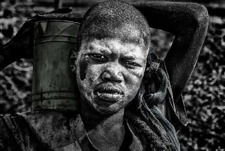 Mundari child carrying a container with milk - South Sudan