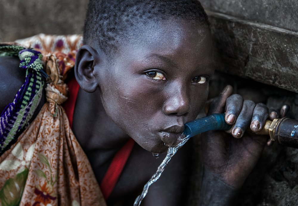 Surmi tribe girl drinking water from a tap - Ethiopia von Joxe Inazio Kuesta Garmendia