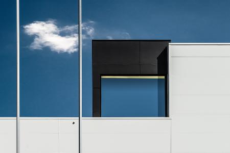 Two flagpoles, a cloud and a window