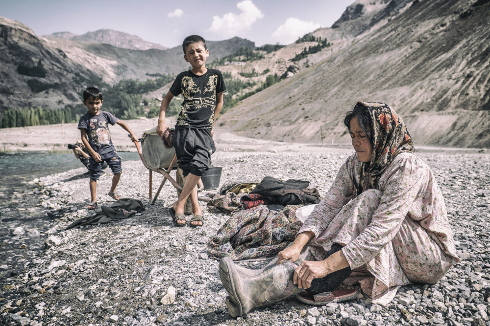 A Tajik woman is preparing to wash in the stream von Marcel Rebro