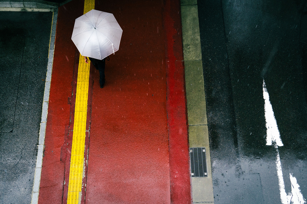 The red sidewalk and a white umbrella von Tetsuya Hashimoto